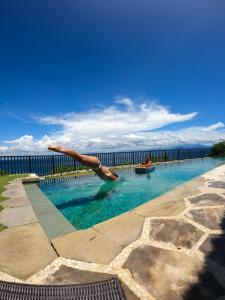 a person diving into a swimming pool near the water at Villa Tanjung in Nusa Lembongan