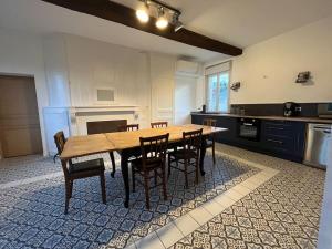 une grande cuisine avec une table et des chaises en bois dans l'établissement Gîte le Presbytère de Blérancourt, à Blérancourt