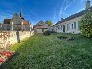 un vieux bâtiment avec un mur et une église dans l'établissement Gîte le Presbytère de Blérancourt, à Blérancourt