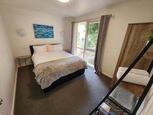 a bedroom with a bed and a large window at Bells Beach Cottages in Bellbrae