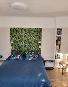a bedroom with a blue bed with a floral headboard at Bel Appartement Bagneres De Luchon Centre in Luchon