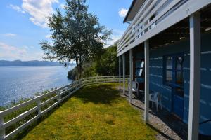 a blue house with a white fence next to the water at Langenuen Motel & Camping in Stord