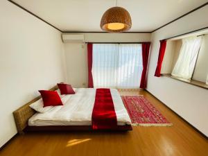 a bedroom with a bed with red pillows on it at Atagohama seaside House in Fukuoka