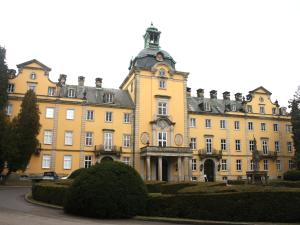 ein großes gelbes Gebäude mit einem Turm darüber in der Unterkunft Hotel Am Schlosstor in Bückeburg