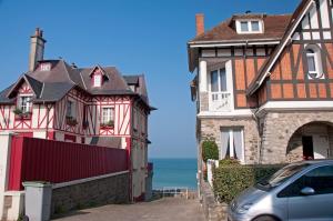 ein Auto, das neben zwei Häusern und dem Meer parkt in der Unterkunft LES ILES VUE SUR MER in Agon Coutainville