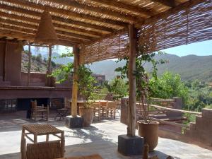 a patio with tables and chairs and a view of a mountain at Ourika Timalizène le jardin des délices in Tamzerdirt