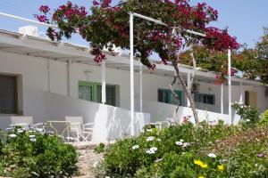 a white building with tables and chairs and flowers at Parasporos Village in Adamas