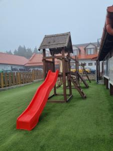 a playground with a red slide on the grass at Kemencés Fogadó 
