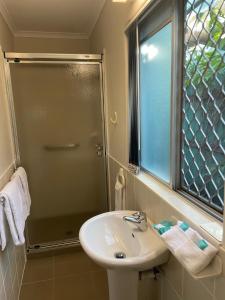 La salle de bains est pourvue d'un lavabo et d'une douche. dans l'établissement Kyamba Court Motel, à Mooloolaba