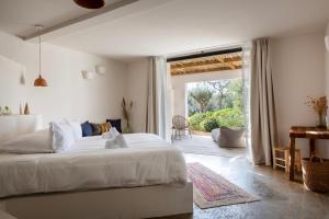 a bedroom with a white bed and a sliding glass door at VILLA FLAKA Boutique Hôtel in Cargèse