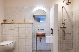 een wit betegelde badkamer met een wastafel en een toilet bij VILLA FLAKA Boutique Hôtel in Cargèse