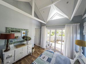 a bedroom with a bed and a mirror and a window at Kalliste an exclusive retreat in Bettyʼs Bay