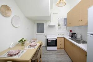 uma cozinha branca com uma mesa e um lavatório em La Rosa em Ermoupoli