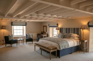 een slaapkamer met een groot bed en 2 stoelen bij Farlam Hall Hotel & Restaurant in Brampton