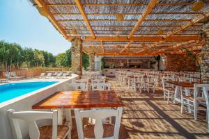 a patio with tables and chairs next to a pool at Coralli Seaside Resort in Livadakia