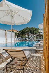 a chair with an umbrella next to a swimming pool at Coralli Seaside Resort in Livadakia