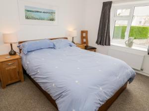 a bedroom with a large bed with blue sheets at 40 Llaneilian Road in Amlwch