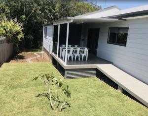 a porch with two chairs and a table on it at Walk to Flynns , Nobbys Beach - Tranquility amongst the Rainforest in Port Macquarie