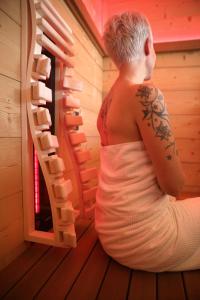 a man with a tattoo sitting in a sauna at Schätzlhof OHG in Ruderting