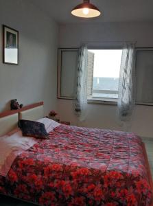 a bedroom with a bed with a red comforter and a window at Fronte mare in Castelsardo