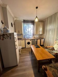 a kitchen with a table and a white refrigerator at Guest house Amazon in Kutaisi