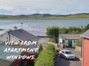a car parked in a parking lot next to a body of water at Blue Door Apartment Main St, Carrigart, F92HC04 in Carrigart