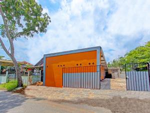 un edificio naranja con una puerta delante de una casa en OYO 91818 Papaya Kos en Cilacap
