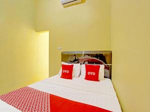 Una cama con almohadas rojas y blancas. en OYO 91818 Papaya Kos en Cilacap