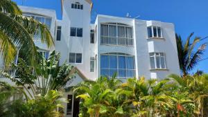 un bâtiment blanc avec des palmiers devant lui dans l'établissement Tropical Palms apartment Mauritius, à Pointe aux Cannoniers