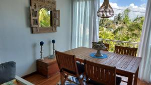 a dining room with a wooden table and a window at Tropical Palms apartment Mauritius in Pointe aux Cannoniers