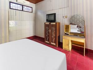 Habitación con cama, TV y escritorio. en OYO 91829 Hotel Artha, en Tjakranegara