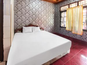 1 dormitorio con 1 cama blanca grande en una habitación en OYO 91829 Hotel Artha, en Tjakranegara