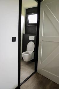 La salle de bains est pourvue de toilettes blanches et d'une porte. dans l'établissement Vakantiewoning 'De Eijk', à Doornspijk
