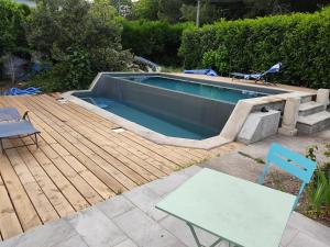einen Pool mit einer Holzterrasse neben einem Tisch in der Unterkunft Little Italy in Mérignac