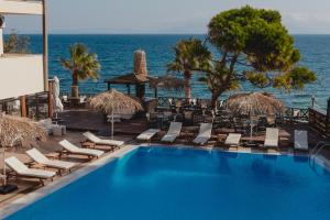 a swimming pool with lounge chairs and the ocean at Mati Hotel in Mati