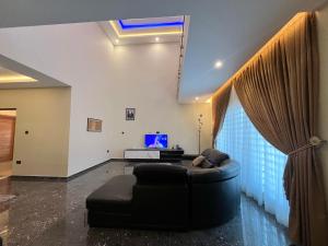 een woonkamer met een zwarte bank en een tv bij Mariaddo homes in Accra