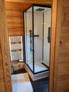 a glass shower in a room with a wooden wall at Chalet La Breche in LʼHuez