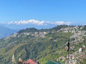 una persona de pie en la cima de una colina con montañas en el fondo en Norbus Homestay en Darjeeling