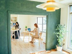 two women sitting at a table with a laptop at ゲストハウスVACILANDO in Chitose