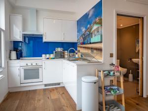 una cocina con armarios blancos y una pared azul en The Shiny Pebble, 5* ground floor.Coastal retreat., en Southwold