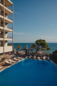 einen Pool mit Stühlen und das Meer im Hintergrund in der Unterkunft Mati Hotel in Mati