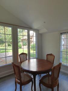 une salle à manger avec une table, des chaises et des fenêtres dans l'établissement Le Logis, à Coulonges-Ardennes