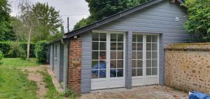 une serre grise avec une porte et un mur en briques dans l'établissement Le Logis, à Coulonges-Ardennes