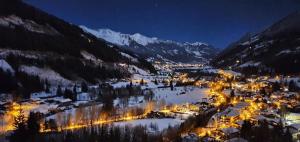 una città nella neve di notte con le luci di Penthousewohnung Gasteinblick a Bad Gastein