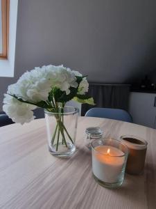 Studio de la Demi Lune في Plobsheim: مزهرية مع الزهور البيضاء وشمعة على الطاولة