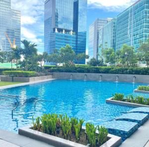 a large swimming pool in a city with tall buildings at Bright 2-bedroom condo with pool in BGC Uptown in Manila