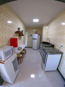 una cucina con elettrodomestici, tavoli e sedie bianchi di Apartamento de frente para o mar a Guarapari