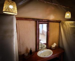 a bathroom with a sink and a mirror and a window at Zawadi Camp in Serengeti