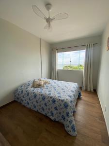 Un dormitorio con una cama con una colcha de flores azul y una ventana en Apartamento de frente para o mar, en Guarapari