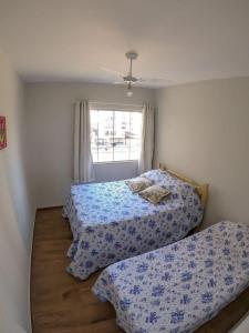 una camera da letto con due letti e una finestra di Apartamento de frente para o mar a Guarapari Altre 12 foto